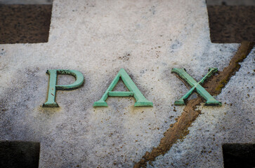 La parola pax scritta in bronzo su una tomba del cimitero monumentale di Milano