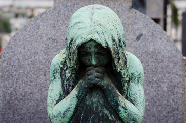 Il volto di bronzo ossidato di una donna sofferente sopra una tomba del cimitero monumentale di...
