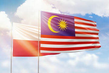 Sunny blue sky and flags of malaysia and poland