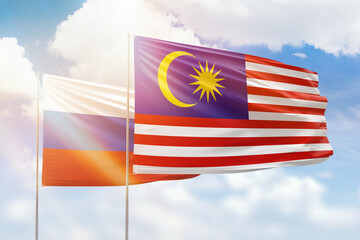 Sunny blue sky and flags of malaysia and russia