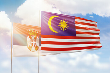 Sunny blue sky and flags of malaysia and serbia