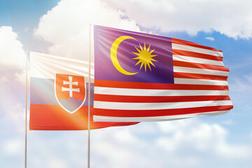 Sunny blue sky and flags of malaysia and slovakia