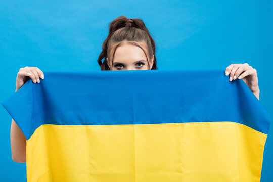 Portrait Of A Woman With Only Her Eyes Visible, Her Face Hidden Behind A Blue And Yellow Flag Of Ukraine, Colorful Background, Expressions Of Solidarity.