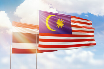 Sunny blue sky and flags of malaysia and thailand