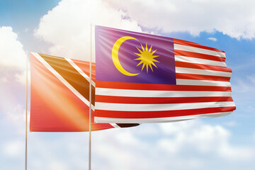 Sunny blue sky and flags of malaysia and trinidad and tobago