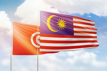 Sunny blue sky and flags of malaysia and tunisia
