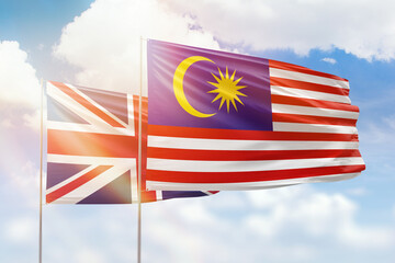 Sunny blue sky and flags of malaysia and united kingdom