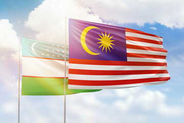 Sunny blue sky and flags of malaysia and uzbekistan