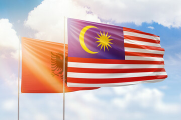 Sunny blue sky and flags of malaysia and albania