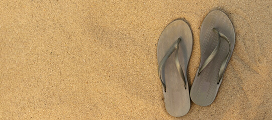 Fototapeta na wymiar banner with light sandal or flip flops on the beach. golden sand. place for your text. top view. flat lay. concept of summer and vacation at sea