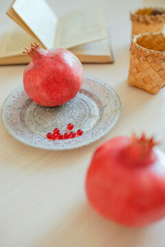 Pomegranates, cookbook, vitamins in plate, mugs on the table