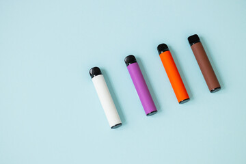Layout of colorful disposable electronic cigarettes on a blue background. The concept of modern smoking