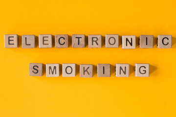 Word electronic smoking written wooden cubes on yellow background