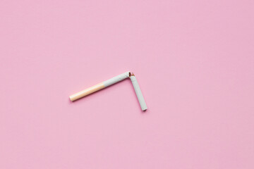 broken cigarette on a pink background