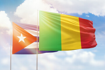 Sunny blue sky and flags of mali and cuba