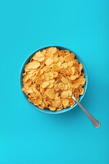 Cornflakes in a blue bowl on a blue background viewed from above. Top view. Copy space