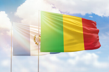Sunny blue sky and flags of mali and guatemala