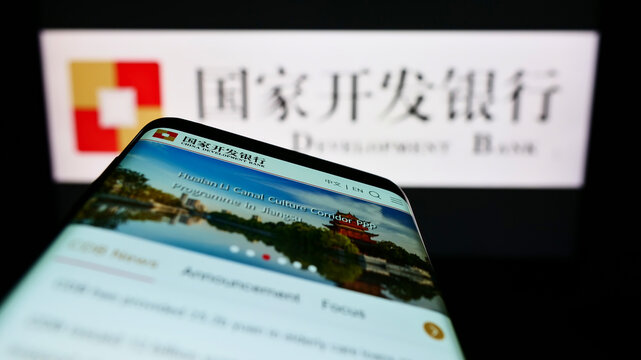 Stuttgart, Germany - 06-12-2022: Person holding smartphone with logo of China Development Bank (CDB) on screen in front of website. Focus on phone display.