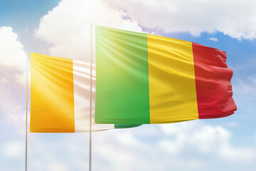 Sunny blue sky and flags of mali and ivory coast