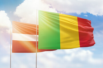 Sunny blue sky and flags of mali and latvia