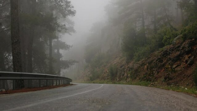 A woman with a backpack walks along the road during heavy fog, a girl walks along a mountain road in rainy weather