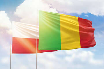 Sunny blue sky and flags of mali and poland