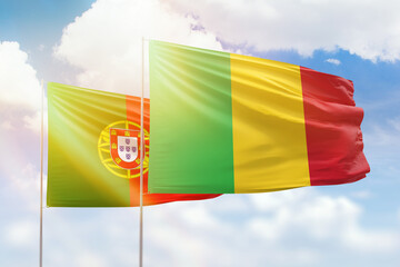 Sunny blue sky and flags of mali and portugal