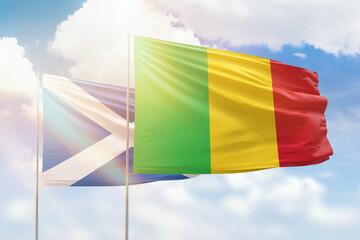 Sunny blue sky and flags of mali and scotland