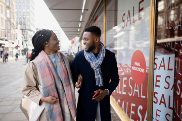 Cheerful Couple Talking and Smiling by Shop Window
