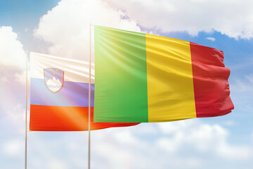 Sunny blue sky and flags of mali and slovenia