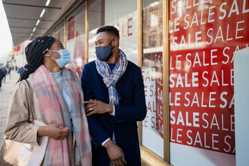 Couple With Faces Covered Walking Past Shop