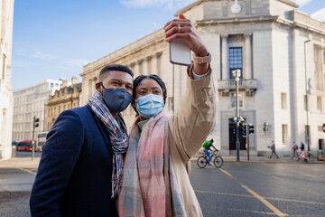 Couple With Face Coverings Taking Selfie