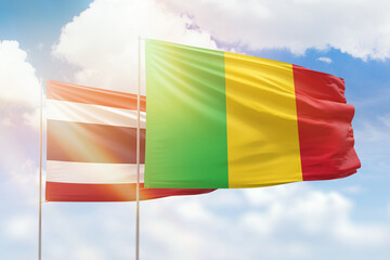 Sunny blue sky and flags of mali and thailand