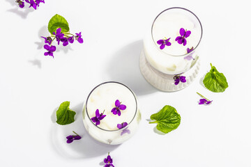 Vegan panna cotta dessert with fresh violet flower. Striped very peri color food, trendy stand