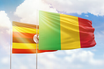 Sunny blue sky and flags of mali and uganda