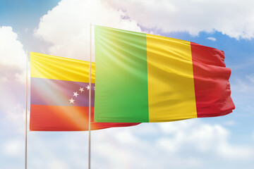 Sunny blue sky and flags of mali and venezuela