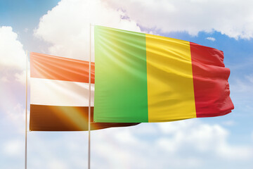 Sunny blue sky and flags of mali and yemen
