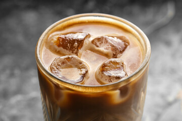Closeup on glass of iced coffee latte on grey background