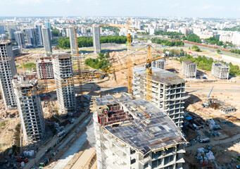Fototapeta premium Сonstruction site with tower cranes on building construction. Builder on formworks. Cranes on pouring concrete in formwork. Tower cranes on construction in built environment. Buildings renovation..