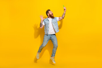 Full length portrait of overjoyed person jump make selfie phone arm wave hi isolated on yellow color background