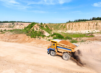 Mining excavator loads sand into dump truck. Excavator loads sand rock into a haul truck. Sand pit...