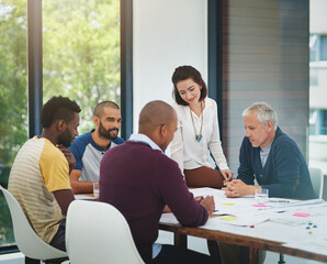 Creative discussions. Cropped shot of a group of architects looking over blueprints during a meeting in the boardroom.
