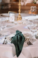 Table setting. On the banquet table there are plates with napkins and name cards, glasses and cutlery