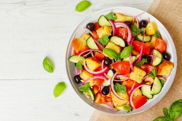 Italian Traditional Dish"Panzanella",mixed salad with tomatoes,breads,cucumbers,red onions,olives,basil,olive oil,salt and peppers on plate with wooden background.Fresh and healthy vegetarian salad