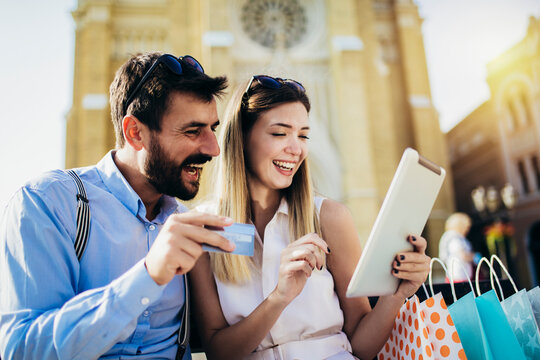 Young couple using credit card and digital tablet for online shopping outdoor.