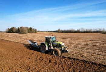 Tractor plowing field. Tractor plow soil cultivating. Cultivated land and soil tillage. Agricultural tractor on farm field cultivation. Tractor disk harrow plowing farm field. Agronomy and agrarian..