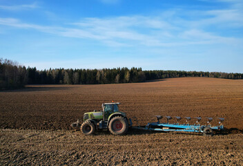 Tractor plow soil cultivating. Green Tractor plowing field. Cultivated land and soil tillage. Agricultural tractor on farm field cultivation. Tractor disk harrow plowing farm field. .