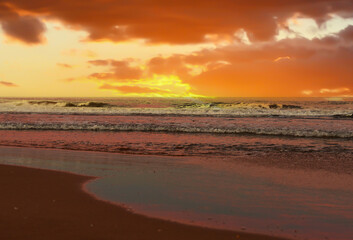 Waves in sea on sunset background. Waves in sea during storm and wind. Wave from the sea goes on land to the beach. Splashing Waves in ocean, background, texture. Wave at Rising Storm. Seashore.