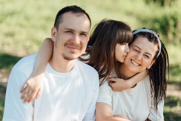 Obraz premium Young family during an outdoor walk, sitting on the lawn, smiling and having fun
