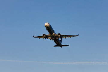 A large modern plane flies in the sky, a view from below from the ground to the belly of the...
